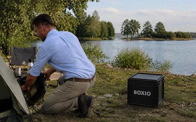Leon installant une toilette sèche BOXIO sur un emplacement de tente au bord d'un lac